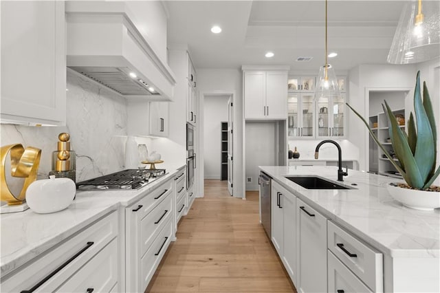 kitchen featuring sink, white cabinetry, hanging light fixtures, appliances with stainless steel finishes, and custom range hood