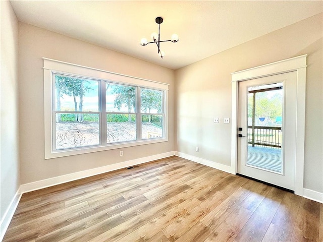 interior space with light hardwood / wood-style floors, a chandelier, and a healthy amount of sunlight