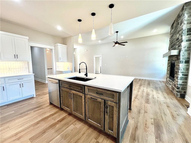 kitchen with white cabinets, dishwasher, an island with sink, sink, and hanging light fixtures