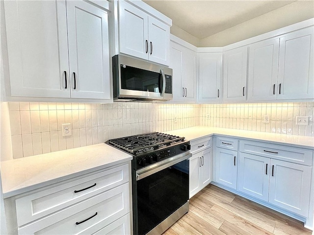 kitchen with decorative backsplash, white cabinets, and gas stove