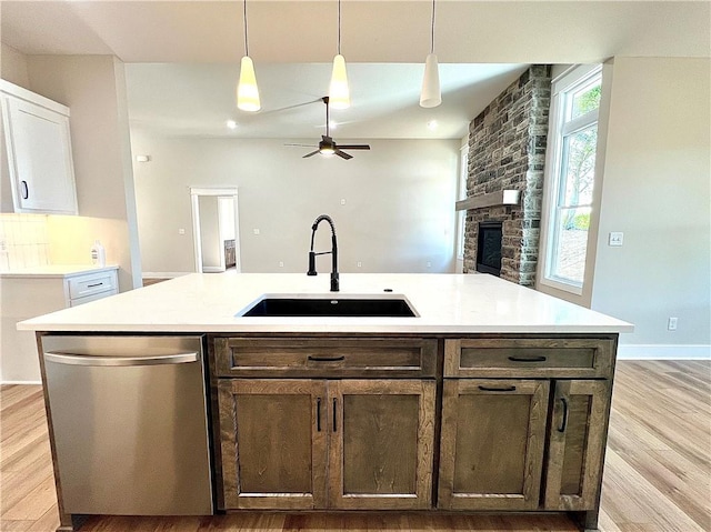 kitchen with decorative light fixtures, dishwasher, sink, an island with sink, and white cabinets