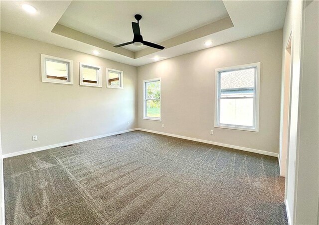 carpeted spare room featuring ceiling fan and a raised ceiling