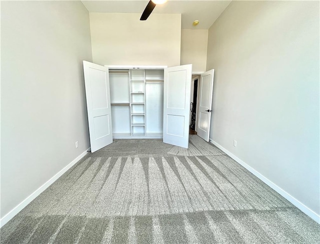 unfurnished bedroom with light carpet, a closet, a towering ceiling, and ceiling fan