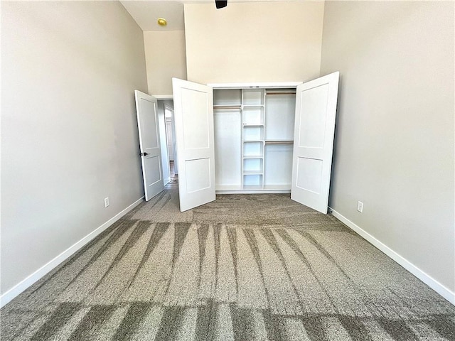 unfurnished bedroom with a closet, carpet flooring, and a towering ceiling