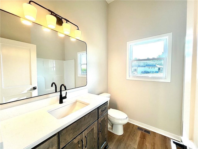 bathroom featuring toilet, walk in shower, wood-type flooring, and vanity