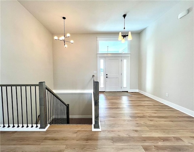 entryway featuring light hardwood / wood-style floors, a high ceiling, and a notable chandelier