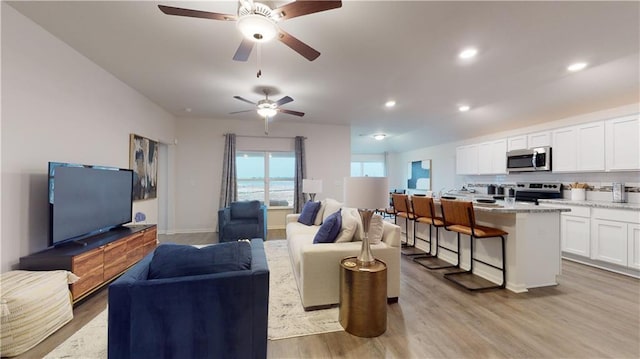 living room featuring ceiling fan and light hardwood / wood-style flooring