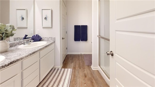 bathroom with vanity, a shower with shower door, and wood-type flooring