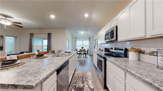 20385 W 193rd Ln, Spring Hill, KS 66083 - kitchen featuring appliances with stainless steel finishes, white cabinetry, wood finished floors, backsplash, and a center island with sink