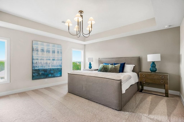 bedroom featuring light colored carpet, a notable chandelier, and a tray ceiling