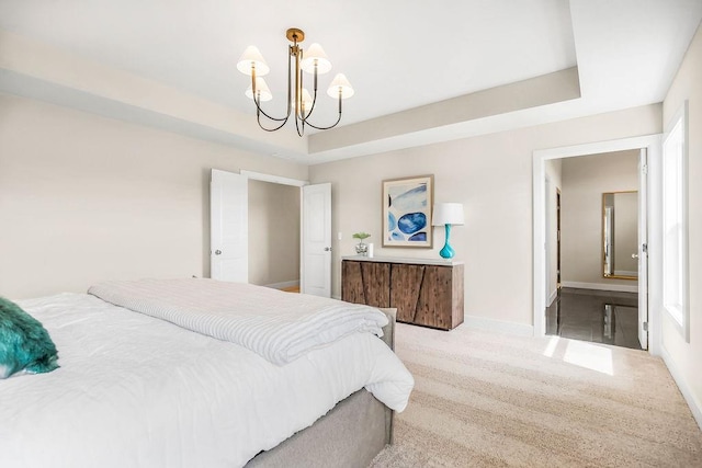 carpeted bedroom with a notable chandelier and a raised ceiling