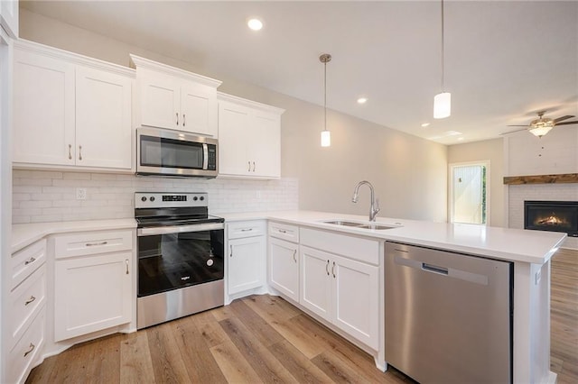 kitchen featuring white cabinetry, stainless steel appliances, kitchen peninsula, and sink