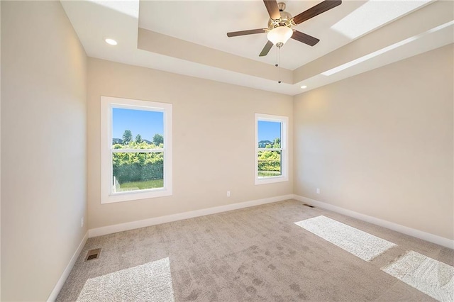 spare room featuring ceiling fan, light colored carpet, and a healthy amount of sunlight