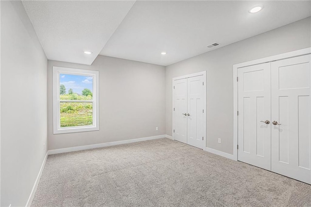 unfurnished bedroom with light carpet and two closets