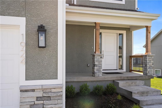 entrance to property with stucco siding, a garage, and covered porch