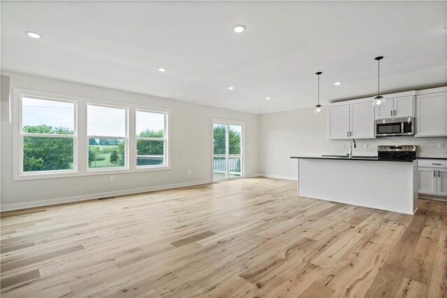 kitchen with stainless steel appliances, white cabinets, light hardwood / wood-style floors, and hanging light fixtures