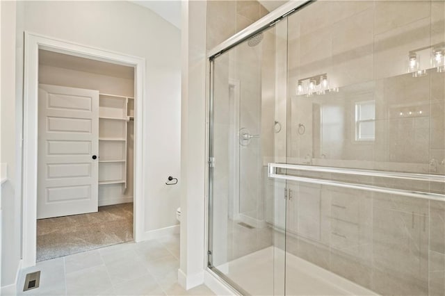 bathroom featuring tile patterned flooring, a shower with shower door, and toilet