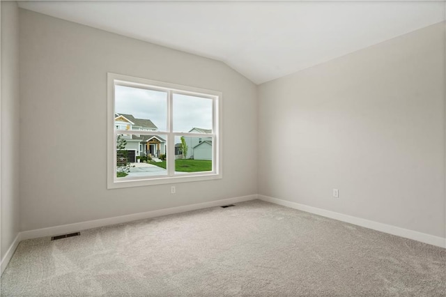 carpeted spare room with vaulted ceiling