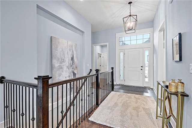 entryway featuring dark wood-style floors, baseboards, and a chandelier