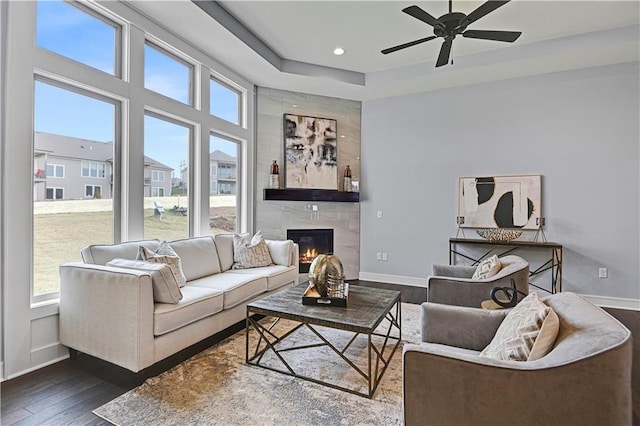 living room featuring ceiling fan, dark hardwood / wood-style flooring, and a fireplace