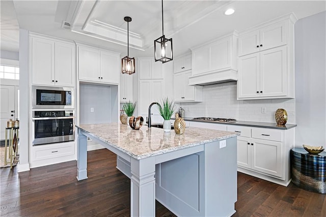 kitchen featuring appliances with stainless steel finishes, a tray ceiling, white cabinetry, and pendant lighting