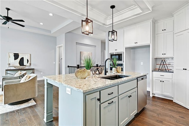 kitchen with a center island with sink, white cabinets, sink, a tray ceiling, and light stone counters