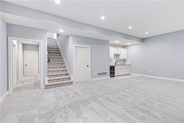 basement featuring sink, light carpet, and beverage cooler