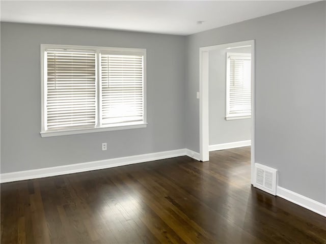 empty room with dark wood-type flooring and a healthy amount of sunlight