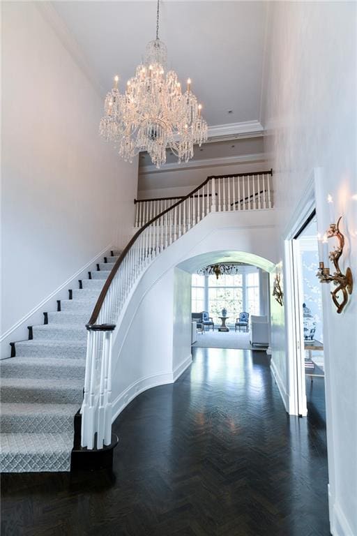 foyer entrance with a high ceiling, dark parquet floors, and a chandelier