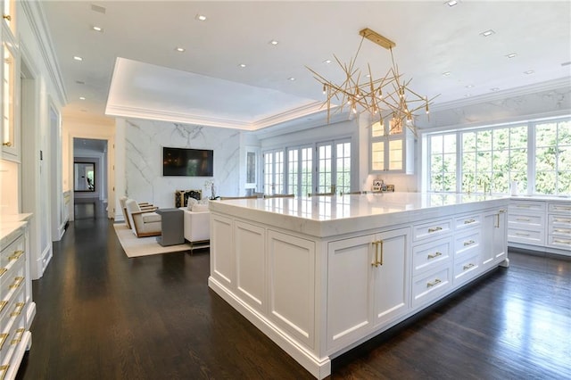 kitchen featuring hanging light fixtures, a high end fireplace, a kitchen island, dark hardwood / wood-style floors, and white cabinets