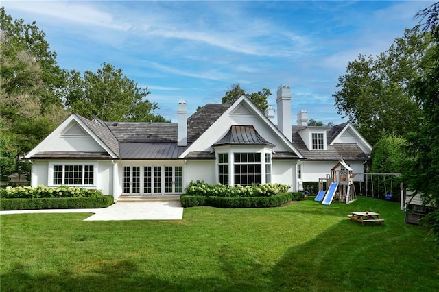 rear view of property with french doors, a playground, a patio area, and a lawn