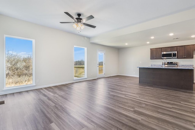 kitchen featuring light stone countertops, appliances with stainless steel finishes, ceiling fan, and dark hardwood / wood-style floors