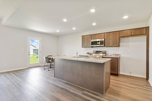 10298 Lucca Ln, Peculiar, MO 64078 - kitchen with appliances with stainless steel finishes, light wood finished floors, recessed lighting, baseboards, and light stone countertops