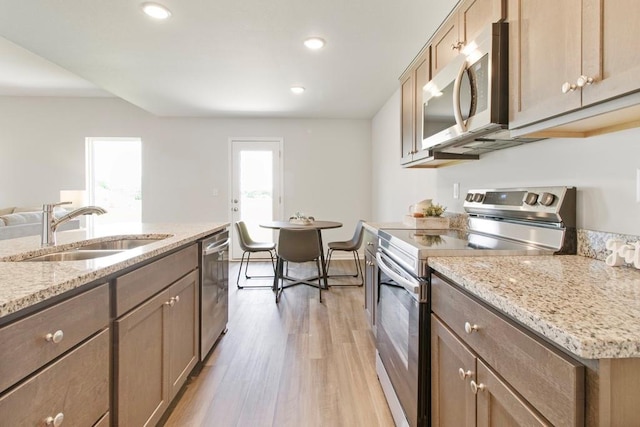10298 Lucca Ln, Peculiar, MO 64078 - kitchen featuring stainless steel appliances, a sink, light wood finished floors, recessed lighting, and light stone countertops