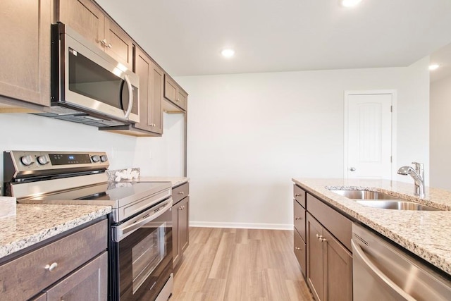 10298 Lucca Ln, Peculiar, MO 64078 - kitchen featuring stainless steel appliances, a sink, light wood finished floors, light stone countertops, and recessed lighting