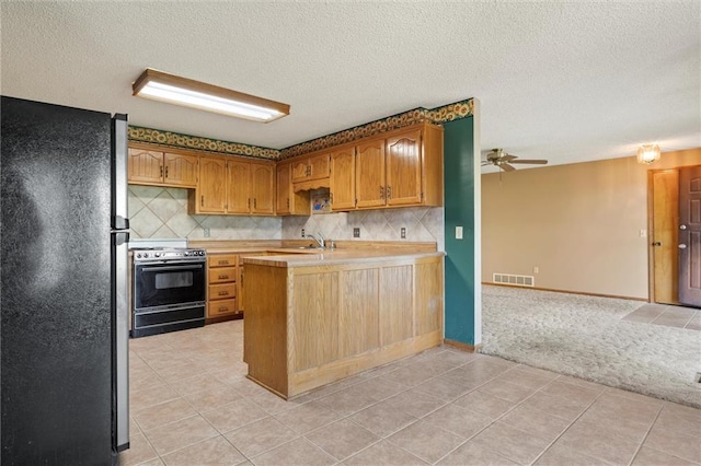 kitchen with electric range, tasteful backsplash, black refrigerator, and light colored carpet