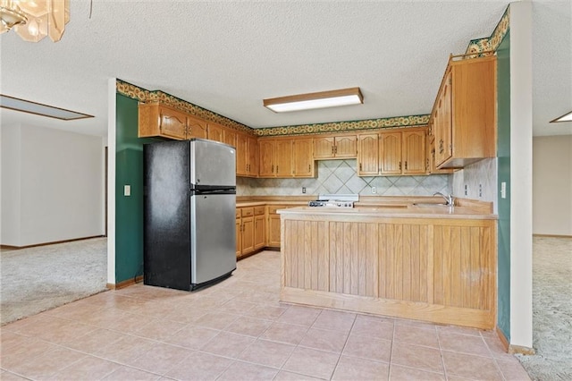 kitchen featuring sink, light colored carpet, stainless steel refrigerator, and backsplash