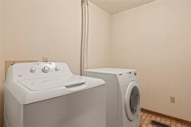 laundry room with independent washer and dryer, a textured ceiling, and light tile flooring