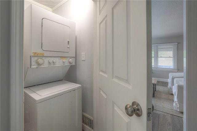 washroom featuring stacked washer and dryer and hardwood / wood-style flooring