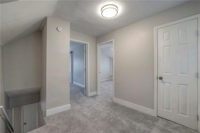 corridor with light carpet and a textured ceiling