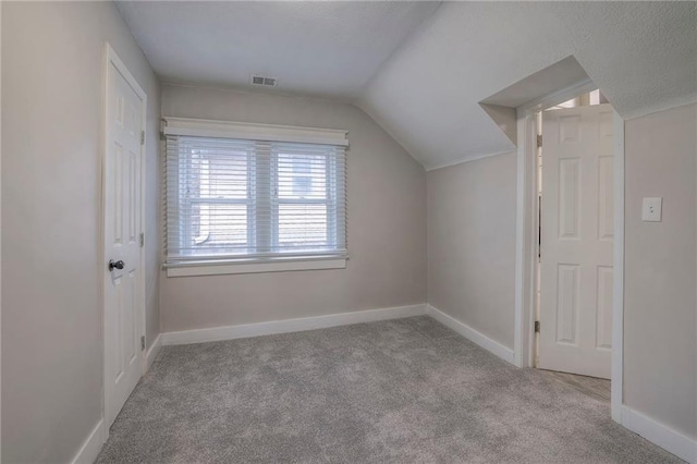 additional living space with light colored carpet and vaulted ceiling