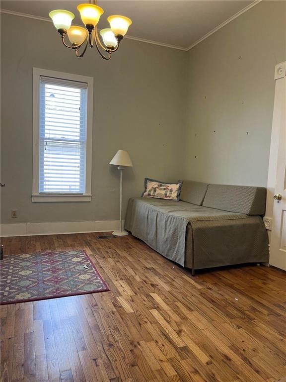 unfurnished bedroom with a notable chandelier, ornamental molding, and hardwood / wood-style floors