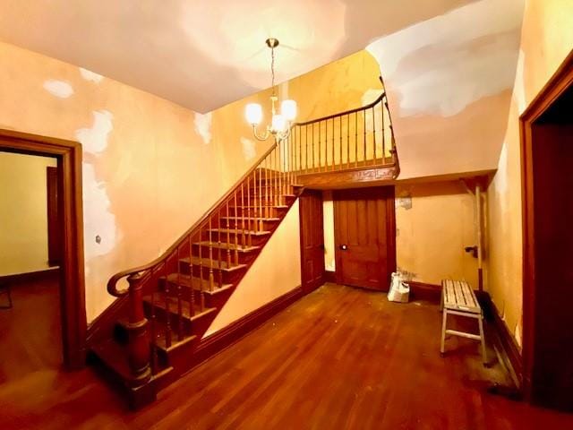 stairway featuring an inviting chandelier and dark hardwood / wood-style flooring