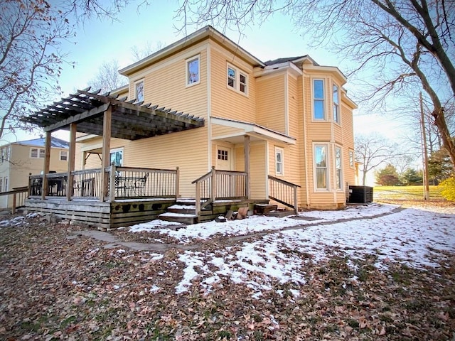 snow covered rear of property featuring a deck, a pergola, and central AC unit