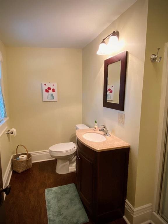 bathroom with wood-type flooring, toilet, and vanity with extensive cabinet space