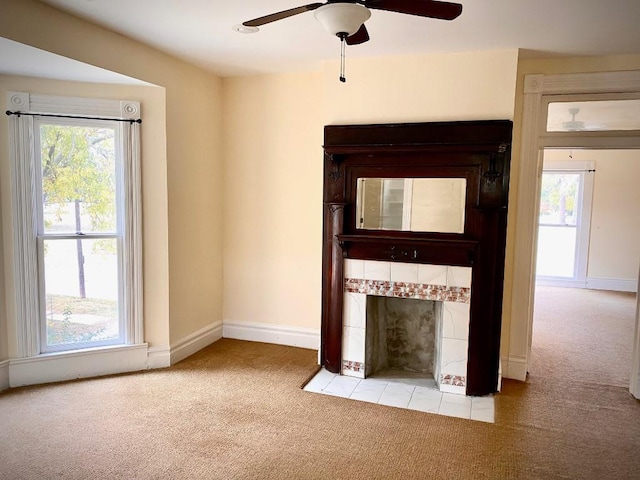 unfurnished living room featuring light carpet, ceiling fan, a healthy amount of sunlight, and a fireplace