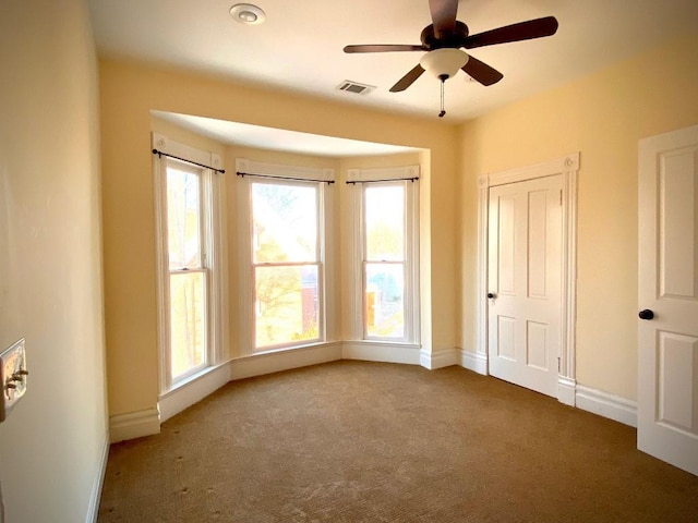 carpeted spare room with ceiling fan and a wealth of natural light