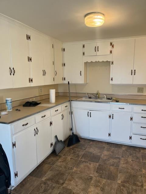 kitchen featuring white cabinets, dark tile flooring, and sink