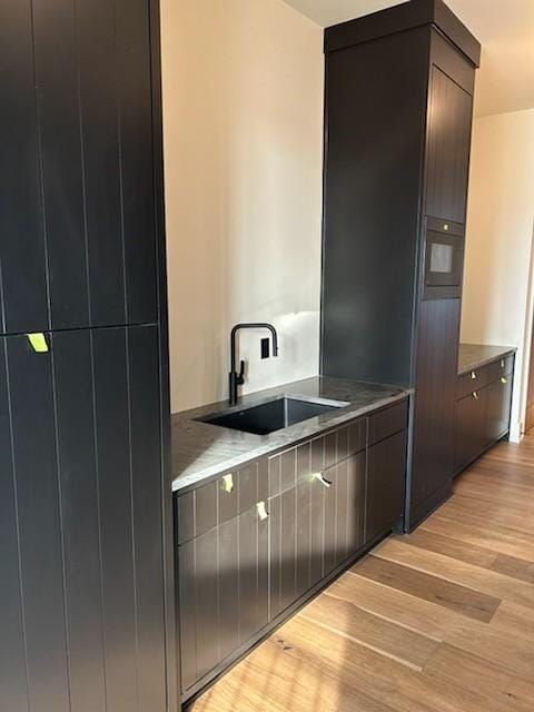 kitchen with dark brown cabinetry, sink, and light hardwood / wood-style floors