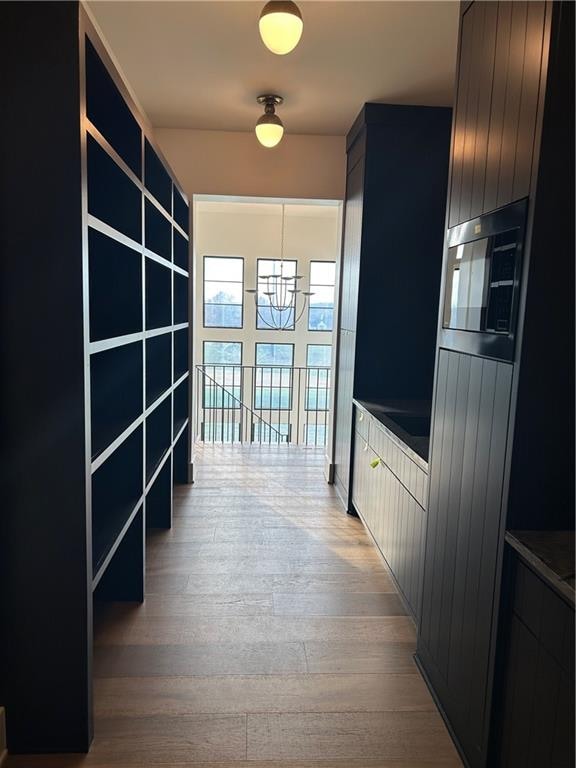 hallway featuring light hardwood / wood-style floors and an inviting chandelier